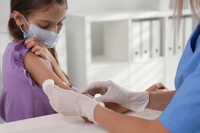 Doctor vaccinating little girl in hospital. Health care