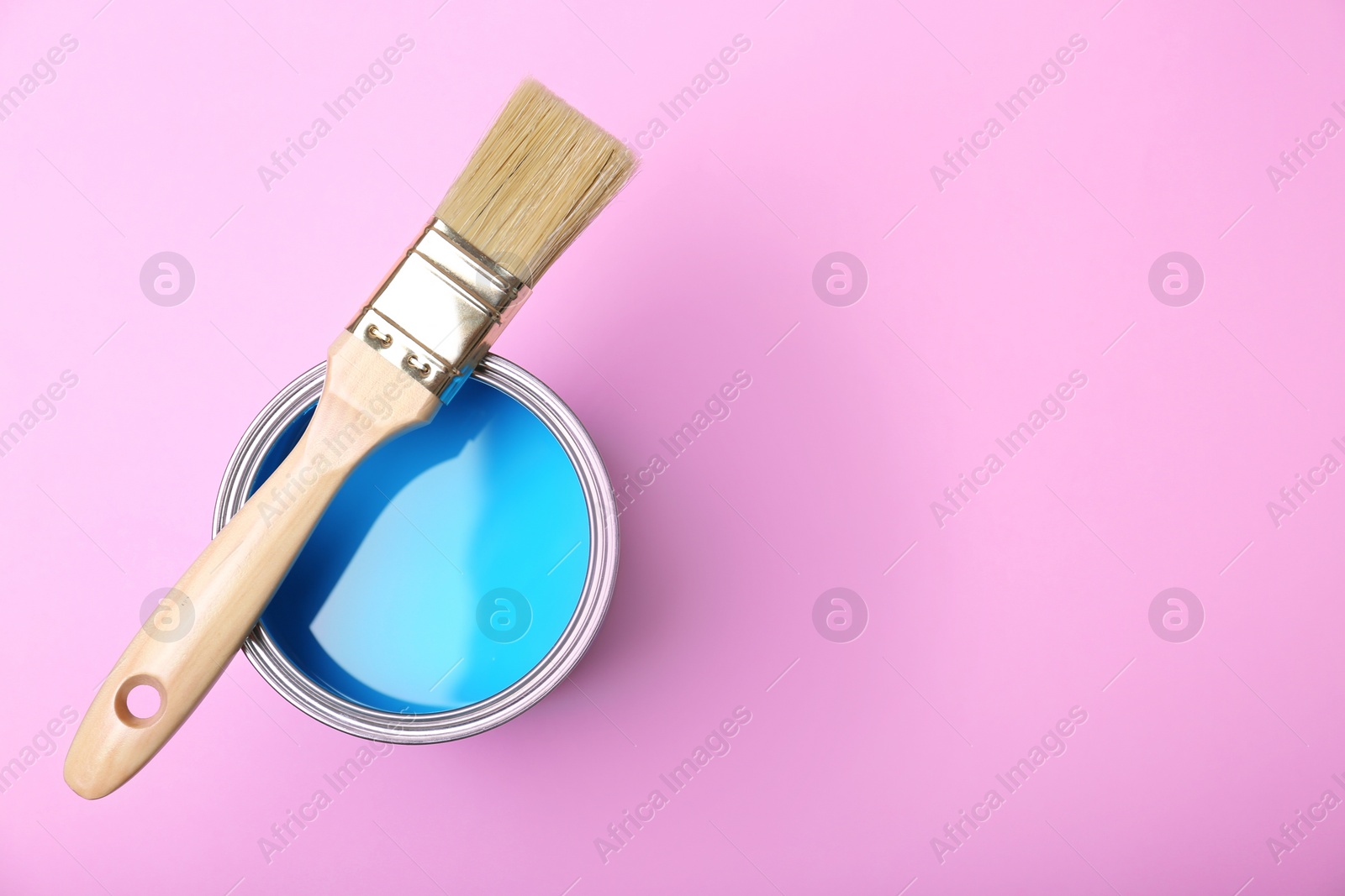 Photo of Paint can and brush on pink background, top view. Space for text