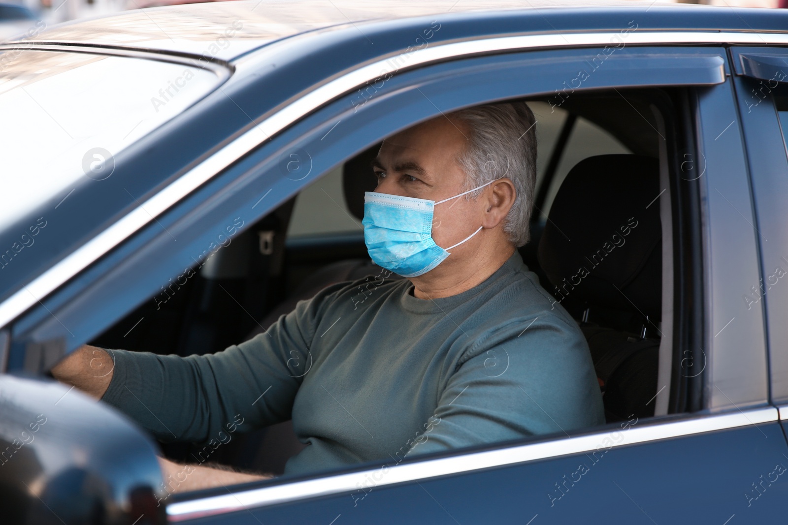 Photo of Senior man with medical mask in car. Virus protection