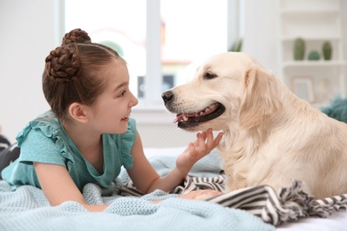 Cute little child with her pet on bed at home