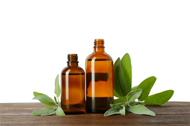 Bottles of essential oil and sage on wooden table against white background