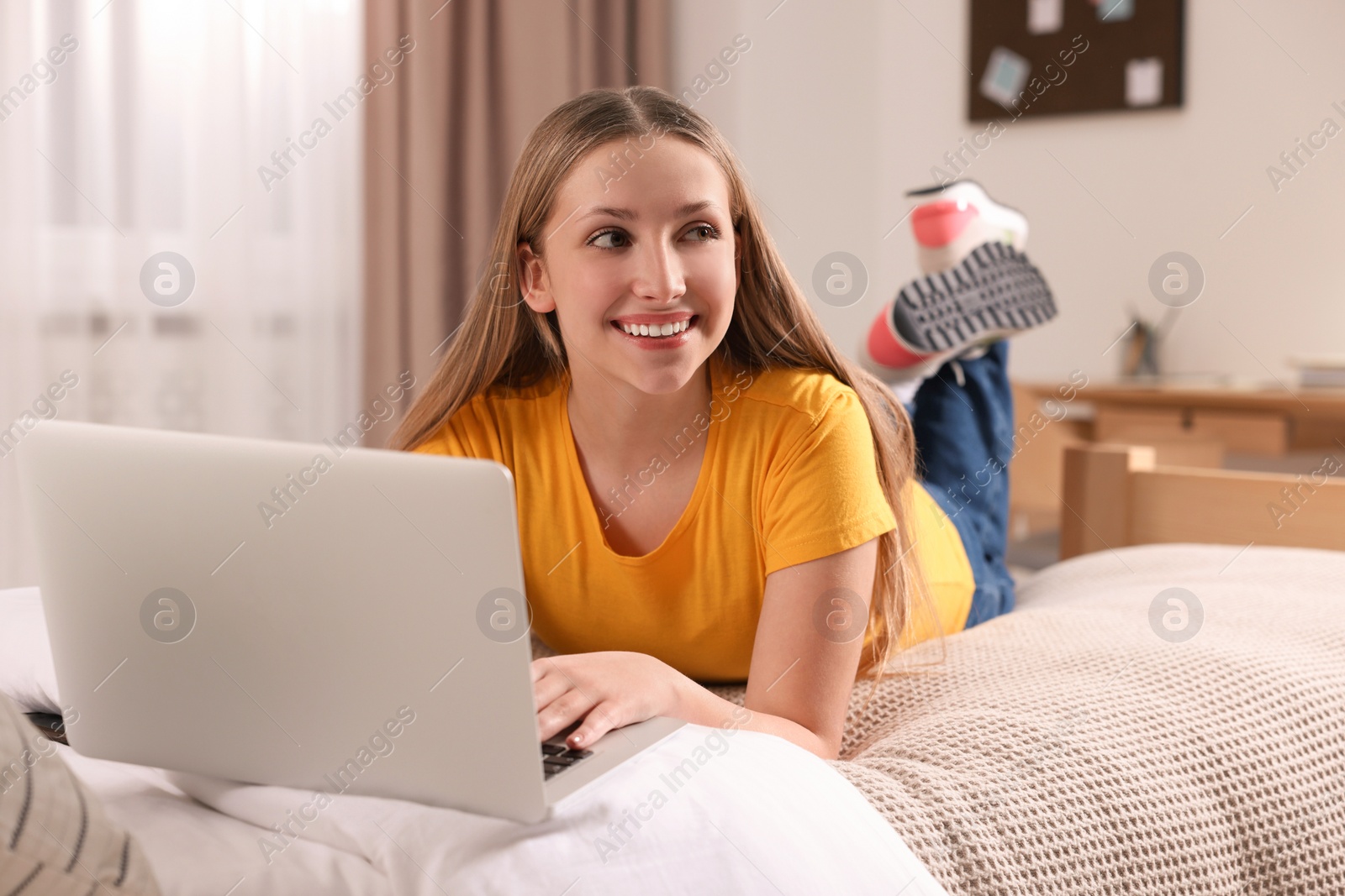 Photo of Online learning. Teenage girl with laptop on bed at home