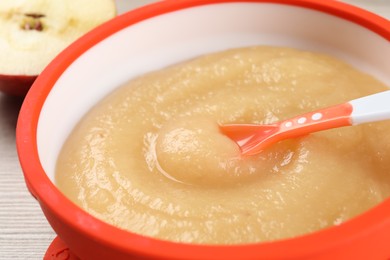 Photo of Healthy baby food. Bowl with delicious apple puree on white wooden table, closeup