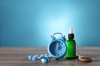Photo of Alarm clock and insomnia remedies on wooden table. Space for text