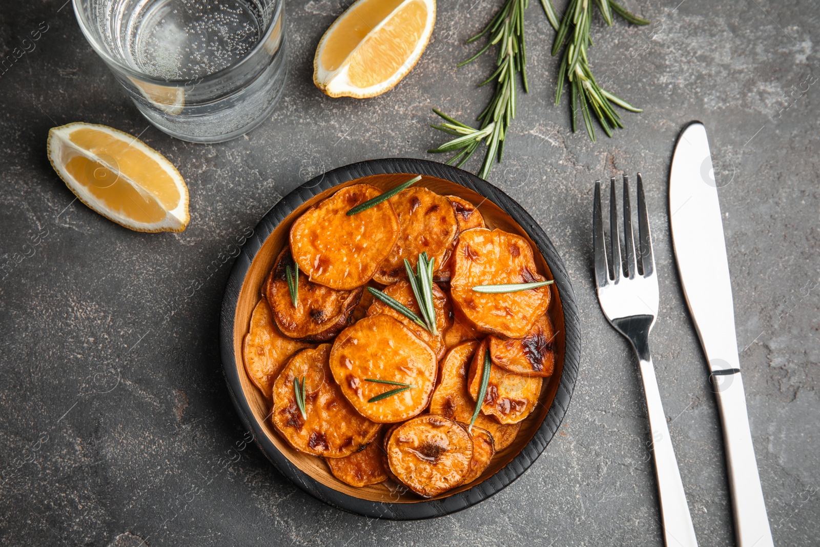 Photo of Plate with baked sweet potato slices served on grey table, top view