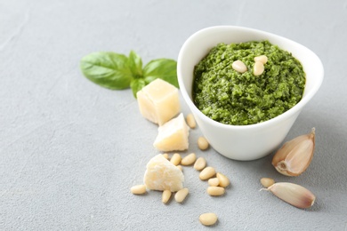 Photo of Composition with bowl of tasty pesto sauce on grey table. Space for text