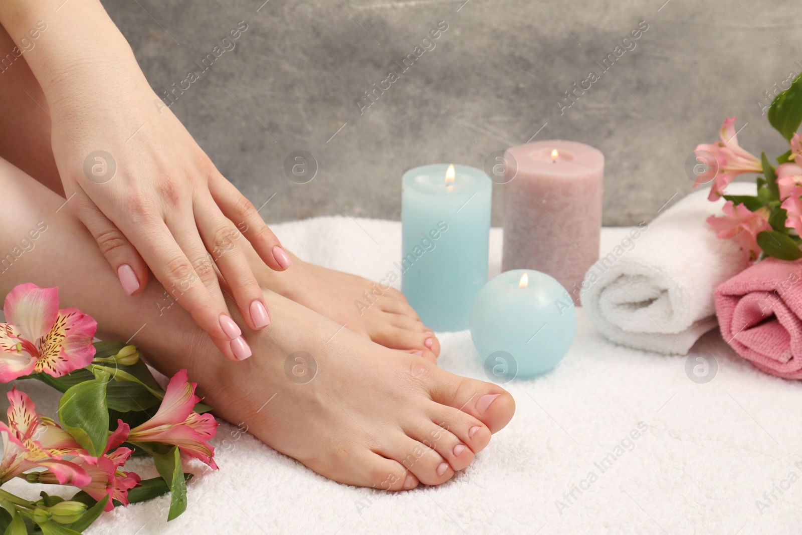 Photo of Woman with neat toenails after pedicure procedure on white terry towel, closeup