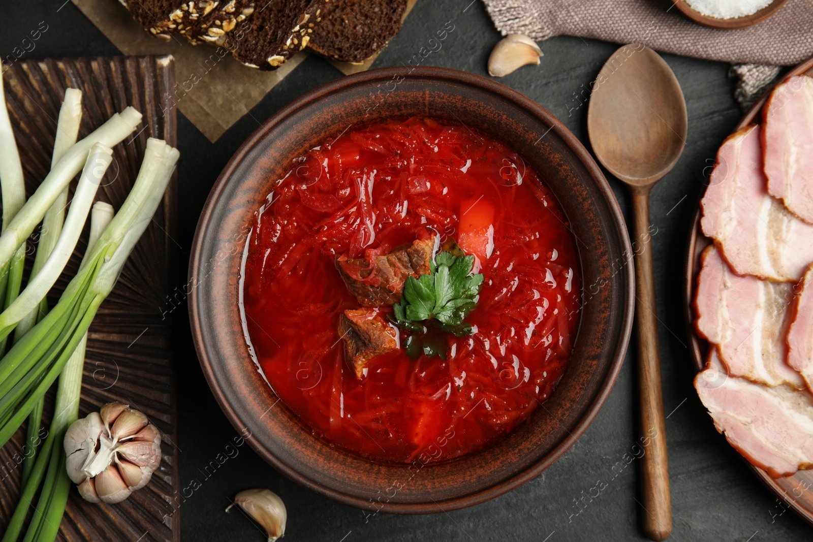 Photo of Stylish brown clay bowl with Ukrainian borsch served on black table, flat lay