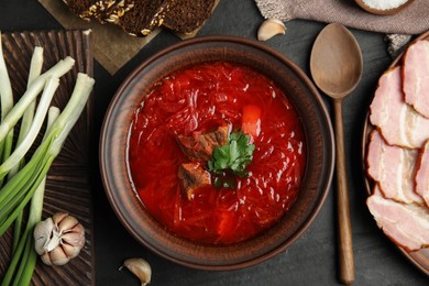 Photo of Stylish brown clay bowl with Ukrainian borsch served on black table, flat lay