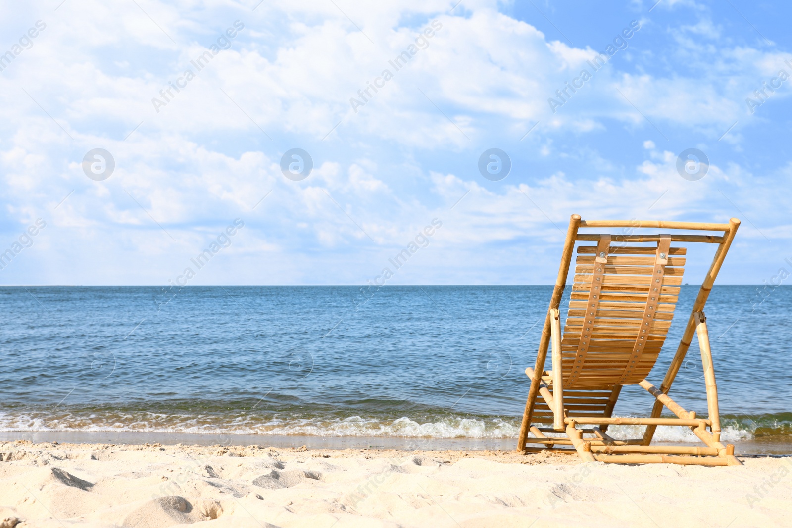 Photo of Sandy beach with empty wooden sunbed on sunny day