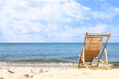 Photo of Sandy beach with empty wooden sunbed on sunny day