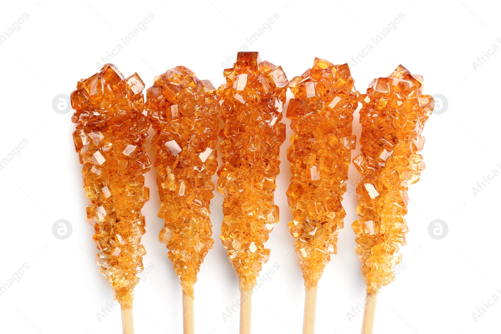 Photo of Wooden sticks with sugar crystals isolated on white, top view. Tasty rock candies