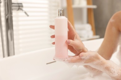 Woman taking bath with shower gel in bathroom, closeup. Space for text