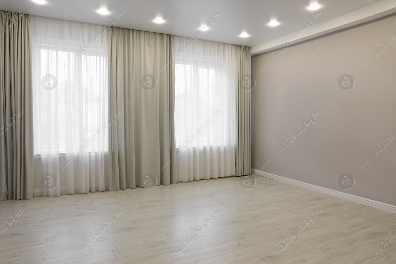 Photo of Empty room with beige wall, large window and wooden floor