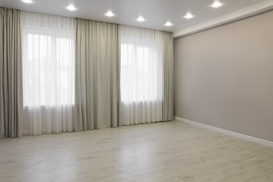 Photo of Empty room with beige wall, large window and wooden floor