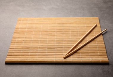 Photo of Bamboo mat and chopsticks on grey table