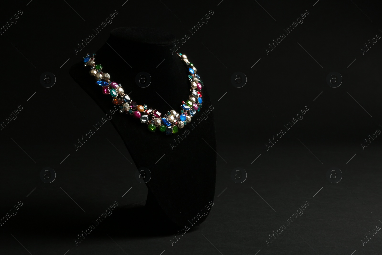 Photo of Elegant necklace on stand against black background, space for text. Luxury jewelry