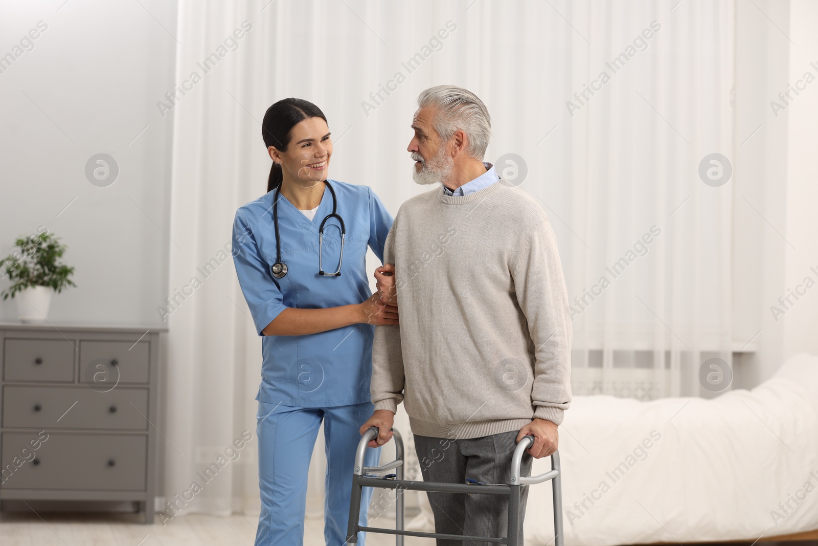 Photo of Smiling nurse talking with elderly patient in hospital