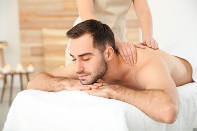 Handsome man receiving back massage in spa salon