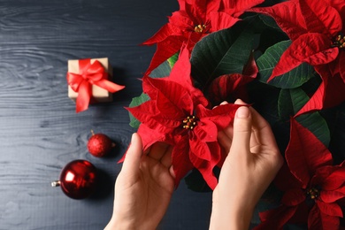 Woman with poinsettia (traditional Christmas flower) at wooden table, closeup