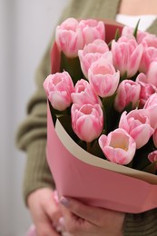 Woman with bouquet of beautiful fresh tulips on blurred background, closeup