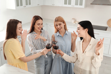 Photo of Beautiful young ladies clinking glasses of wine in kitchen. Women's Day