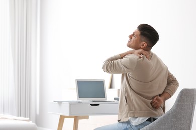 Photo of Man suffering from back pain at workplace. Bad posture problem
