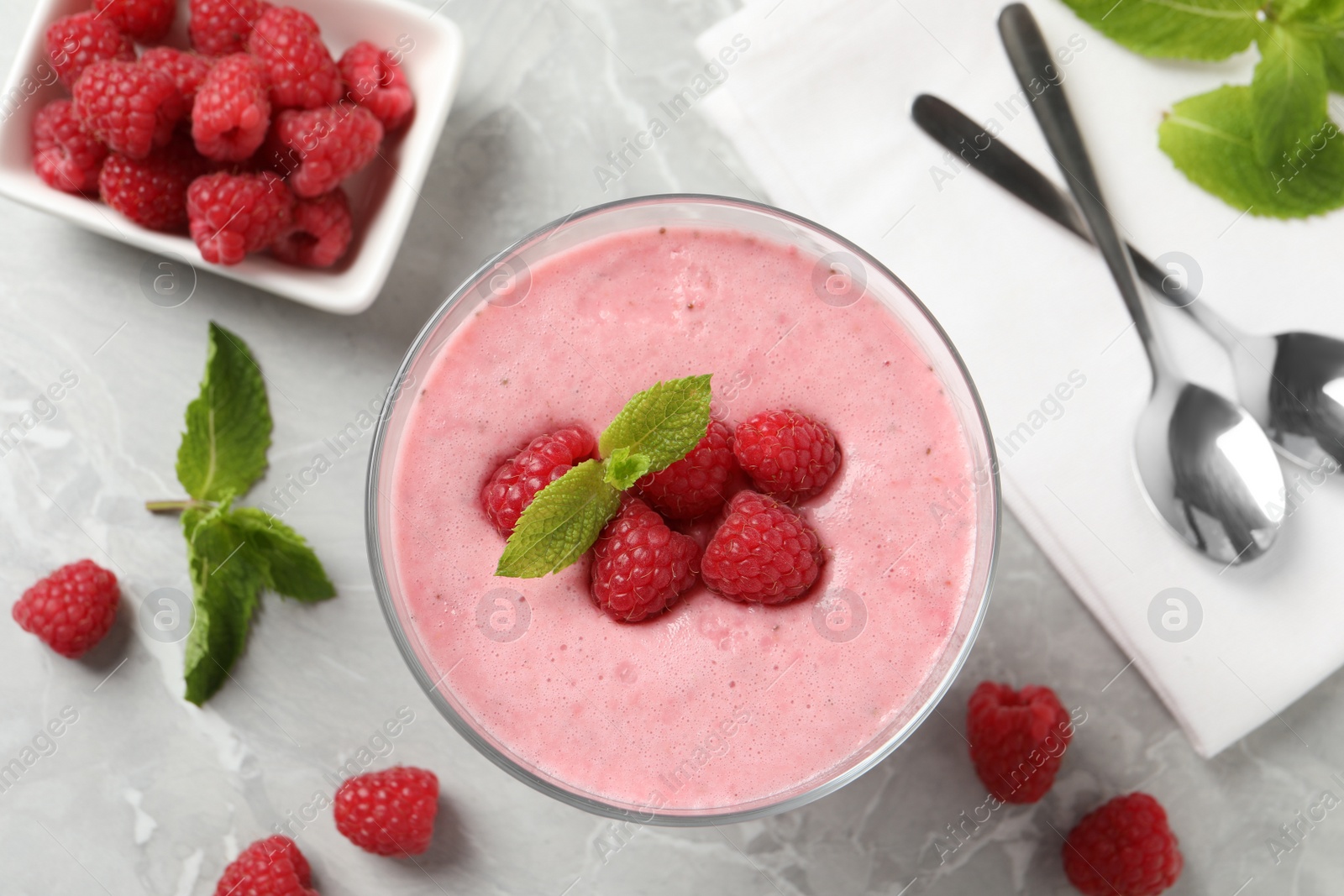 Photo of Delicious raspberry mousse with mint on grey marble table, flat lay