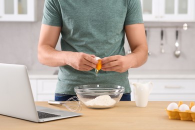 Photo of Man learning to cook with online video at wooden table in kitchen, closeup. Time for hobby