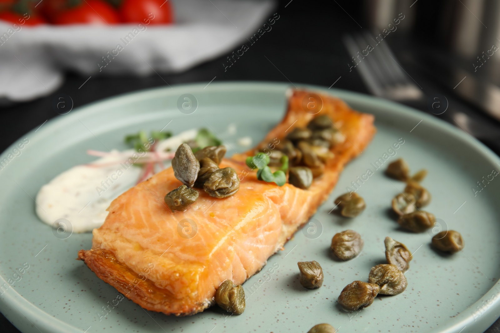 Photo of Delicious salmon with capers and sauce on plate, closeup