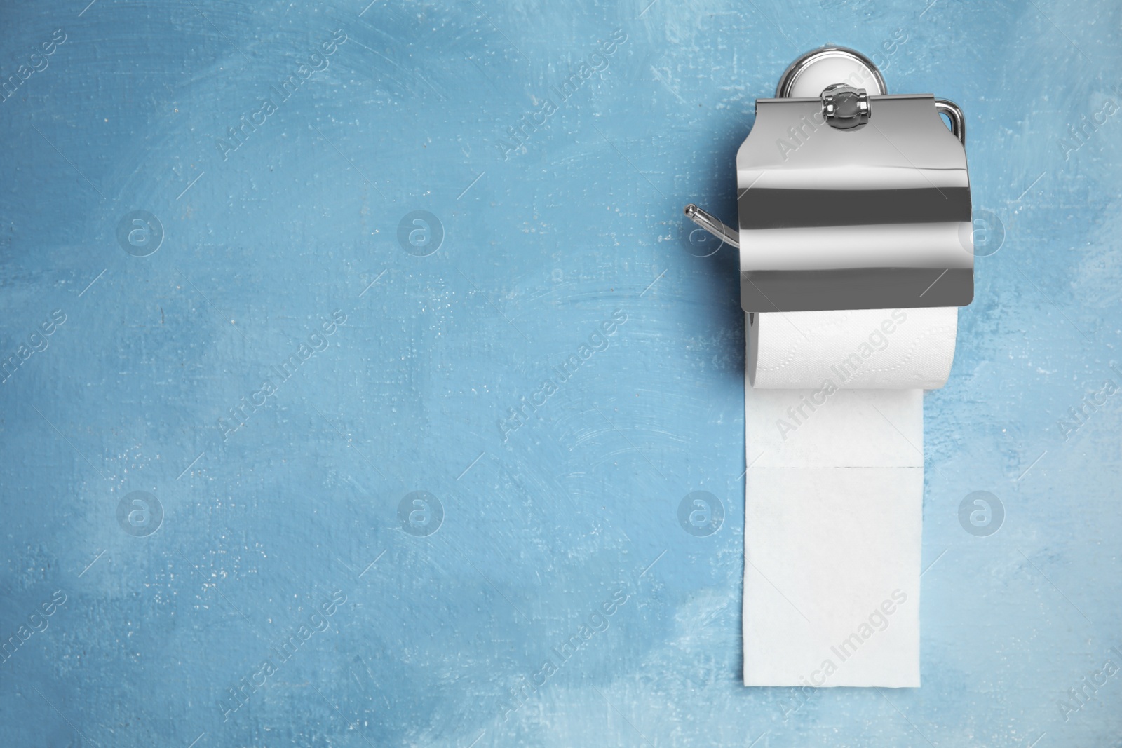 Photo of Toilet paper holder with roll on color background. Space for text