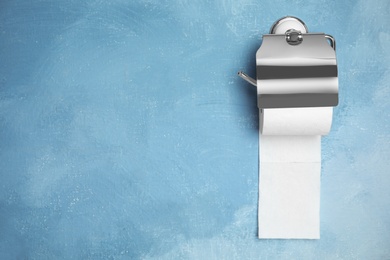 Photo of Toilet paper holder with roll on color background. Space for text