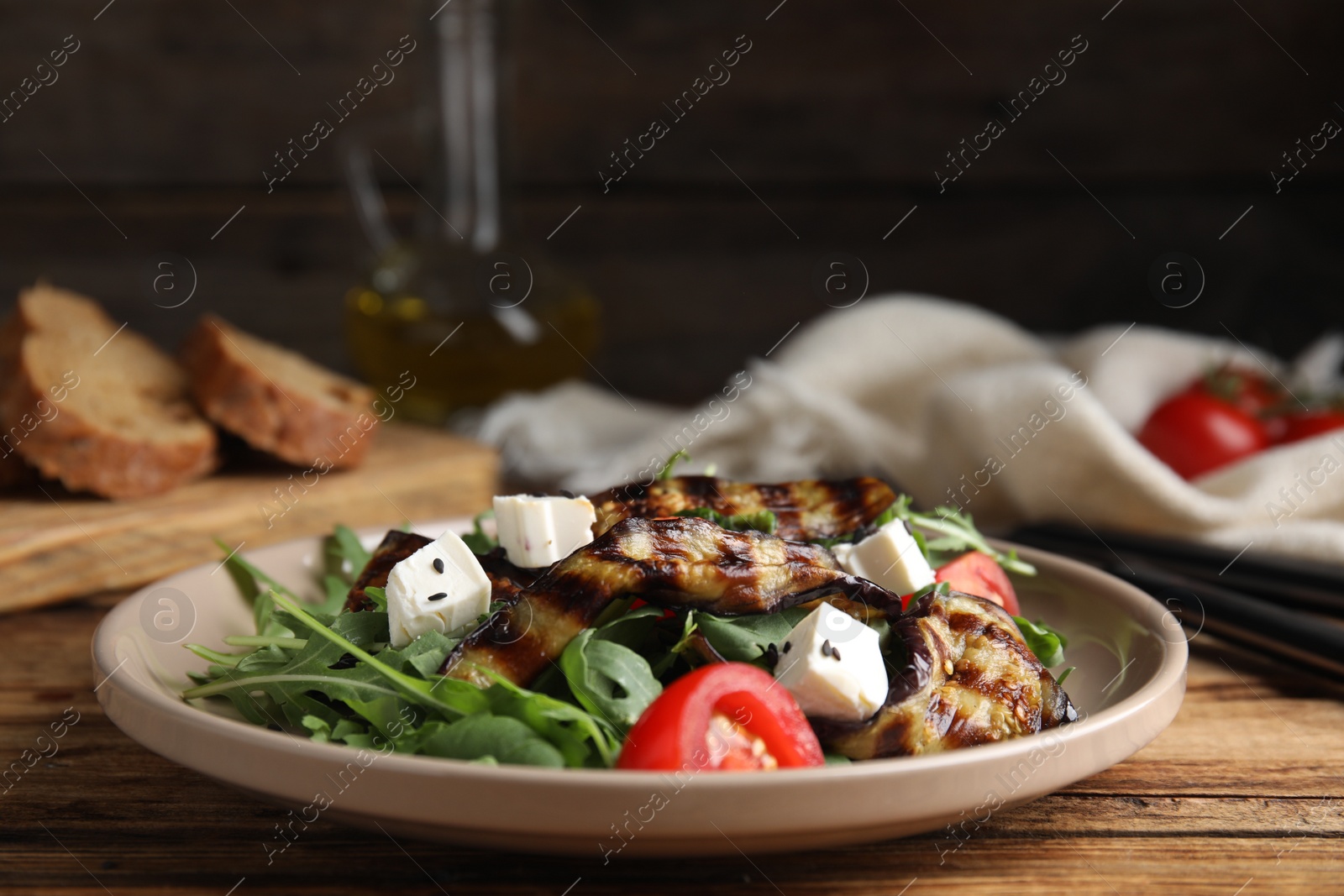 Photo of Delicious salad with roasted eggplant, feta cheese and arugula served on wooden table