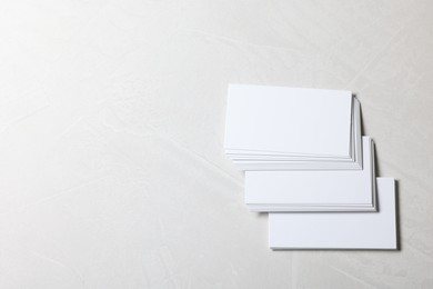 Blank business cards on light grey textured background, top view. Mockup for design