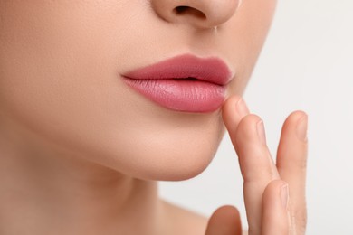 Photo of Young woman with beautiful full lips on white background, closeup