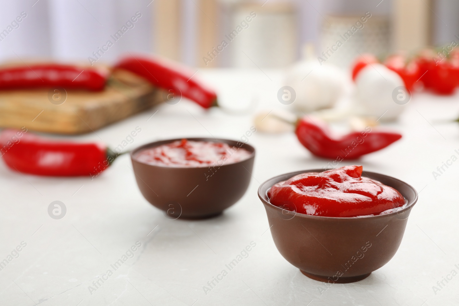 Photo of Bowls with spicy chili sauce on light table