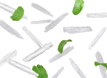 Image of Translucent menthol crystals and green mint leaves falling on white background 