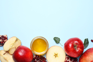 Photo of Honey, apples and pomegranates on light blue background, flat lay with space for text. Rosh Hashanah holiday