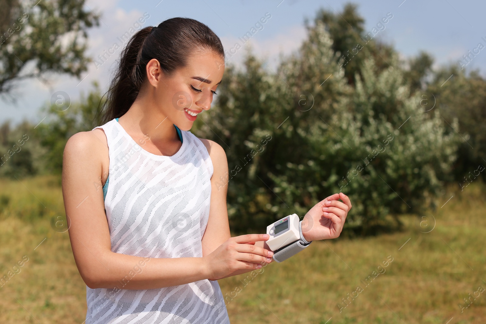 Photo of Young woman checking pulse with medical device after training in park. Space for text
