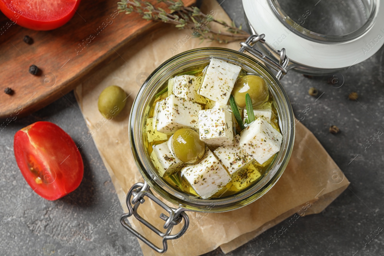 Photo of Flat lay composition with pickled feta cheese in jar on grey table