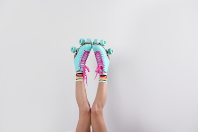 Young woman with retro roller skates on white background, closeup