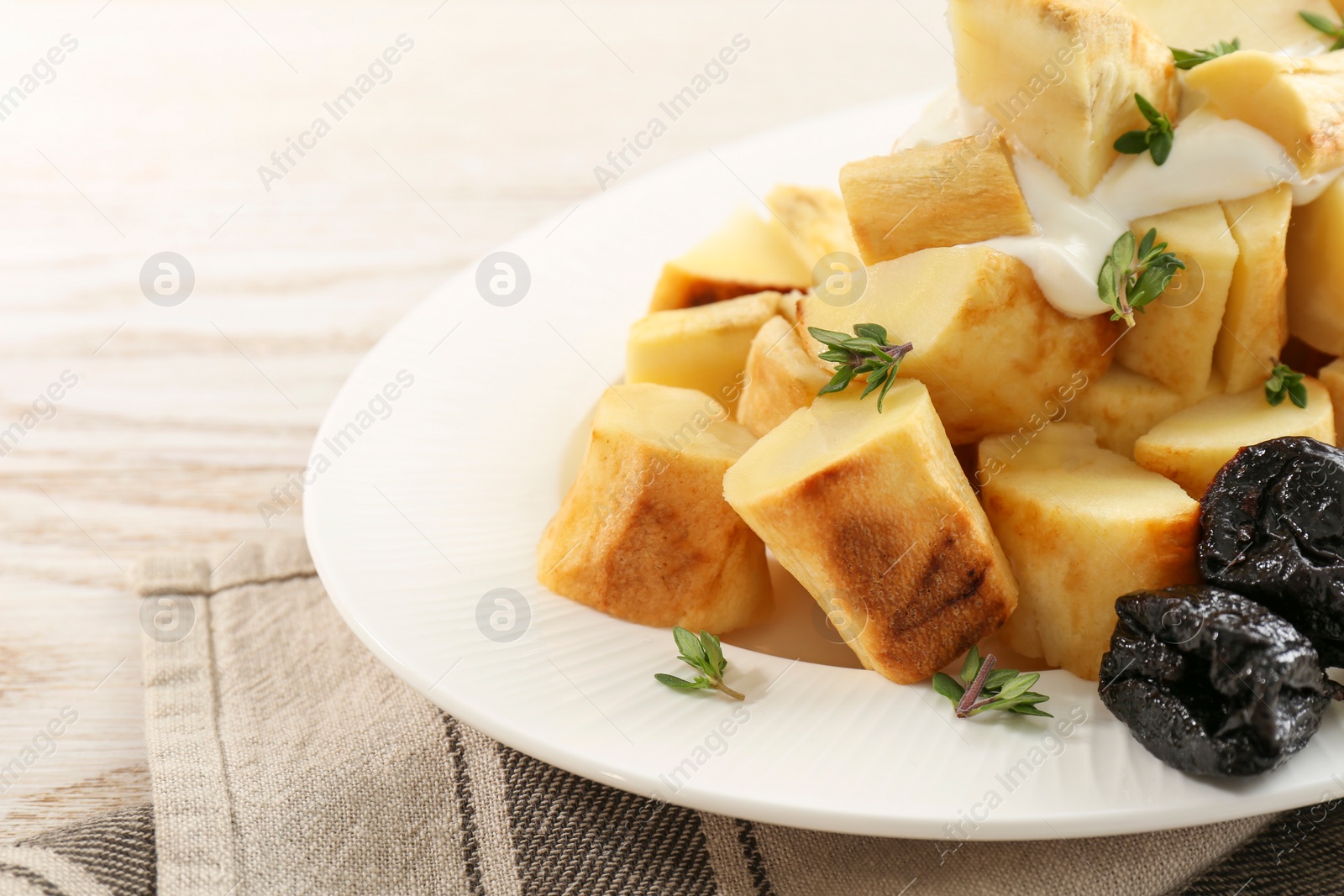Photo of Tasty homemade parsnips with prunes and thyme on white wooden table, closeup. Space for text