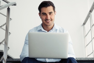 Photo of Portrait of young man with laptop indoors