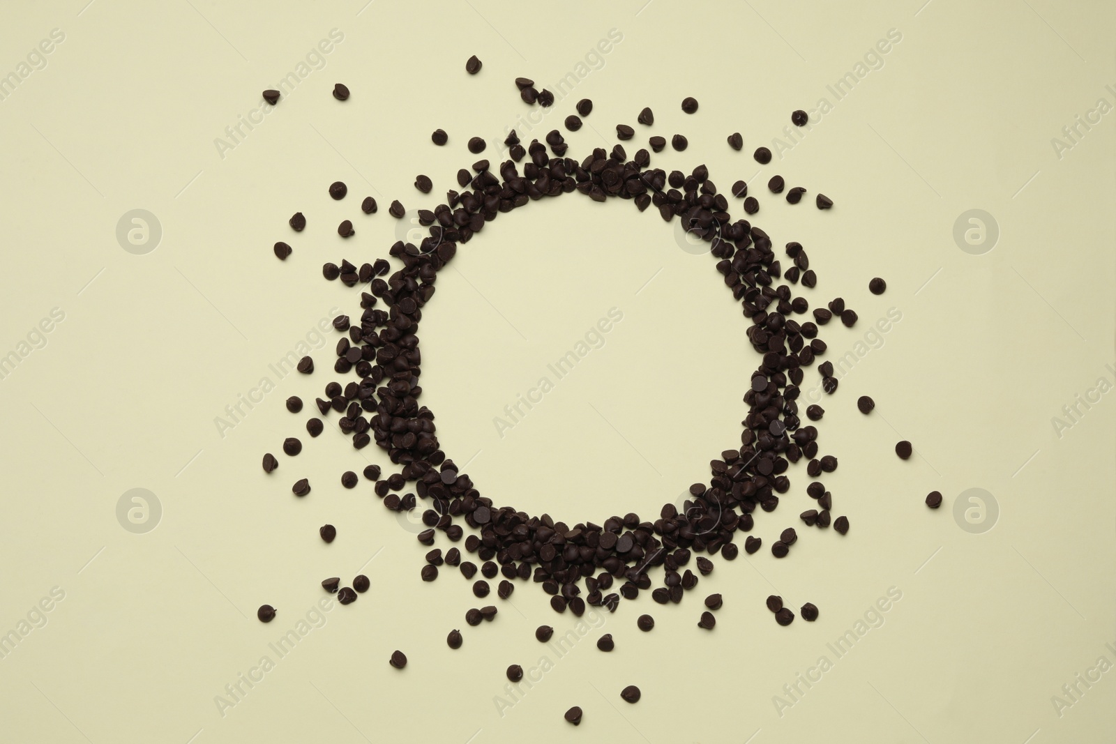 Photo of Circle made of delicious chocolate chips on beige background, top view. Space for text