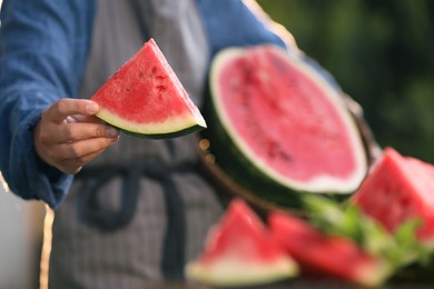 Closeup view of woman holding watermelon outdoors, focus on hand. Space for text
