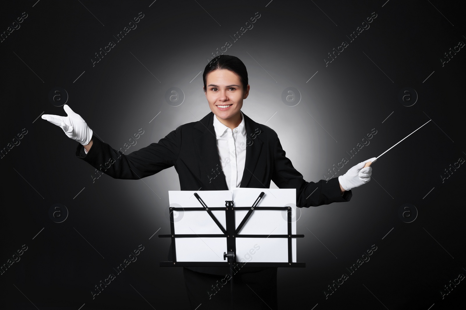 Photo of Professional conductor with baton and note stand on black background