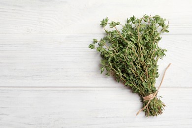 Photo of Bunch of aromatic thyme on white wooden table, top view. Space for text