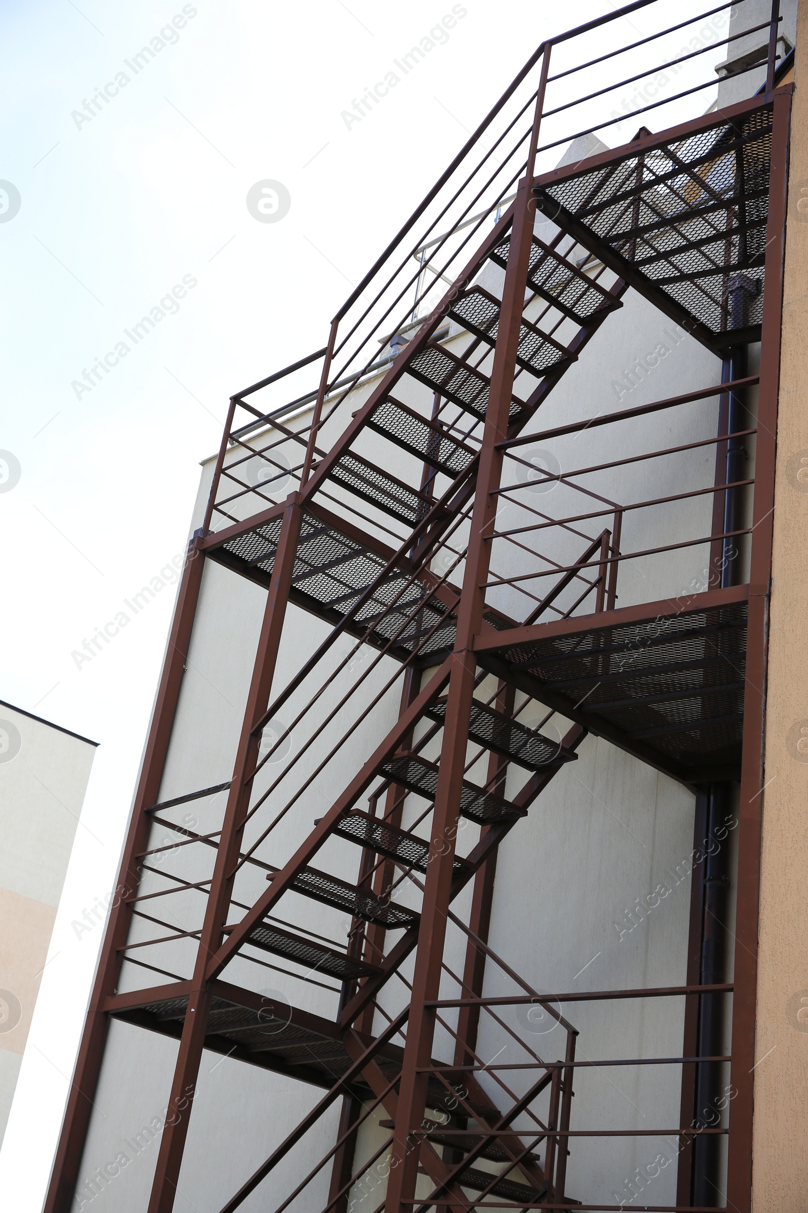 Photo of Metal fire escape ladder near building outdoors, low angle view