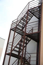 Metal fire escape ladder near building outdoors, low angle view
