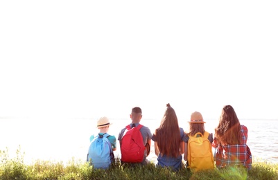 Group of children with backpacks on coast. Summer camp